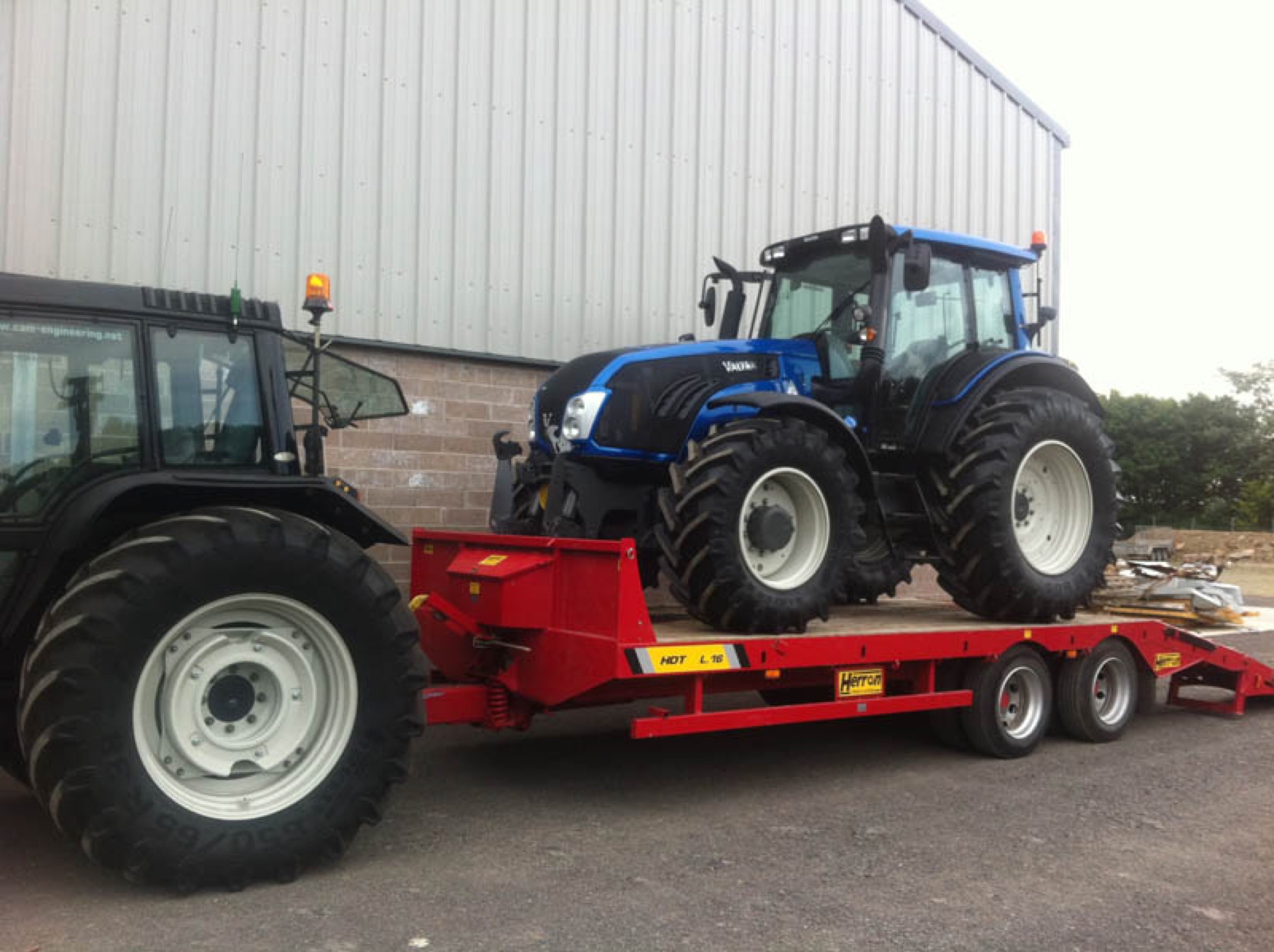 A Valtra tractor loaded on a low-loader outside the yard.